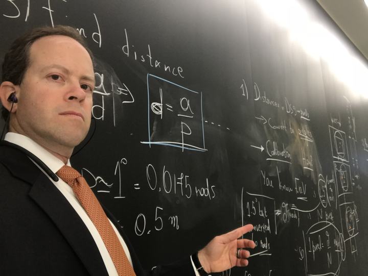 Russ Rosenzweig at a chalkboard, working through an angular-distance calculation